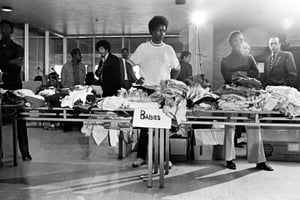 Members of the Black Panther Party stand behind tables ready to distribute free clothing to the public in New Haven, Connecticut, 1969.